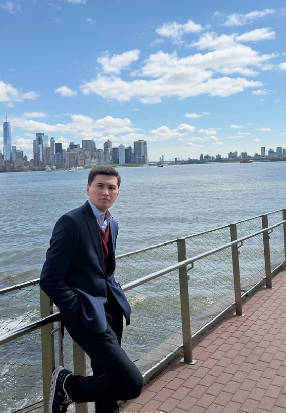 Mehrojbek Makhmudov beside the waterfront with the New York skyline across the water.