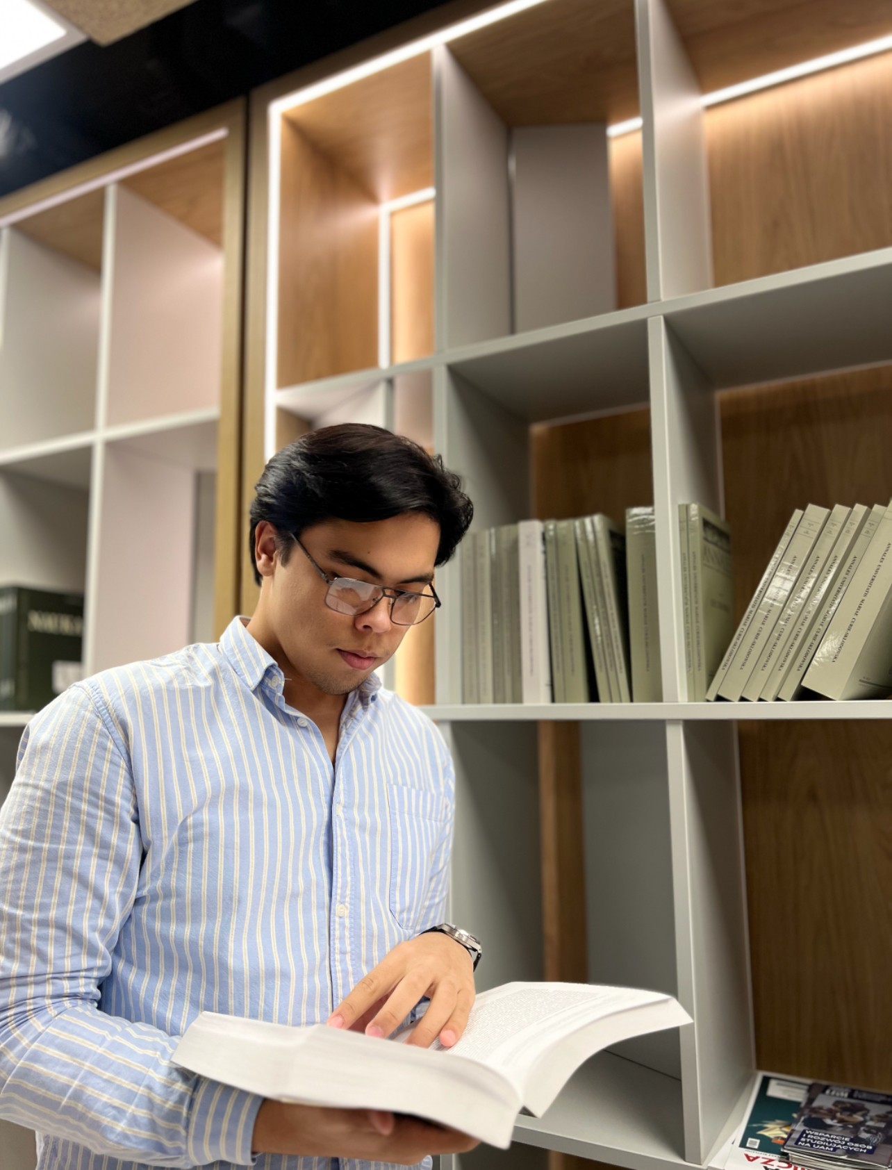 Ulugbek Kodirov reading a book in a library.